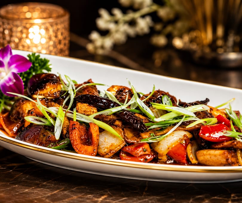 Stir-fried vegetables and mushrooms in a rich dark sauce, garnished with fresh green onions.